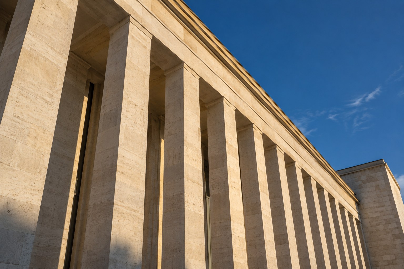 Sunlit limestone columns seen from below against a deep blue sky